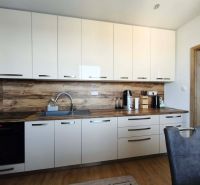 Küche in einer 3-Zimmer-Wohnung mit weißen Schränken und Holzboden.