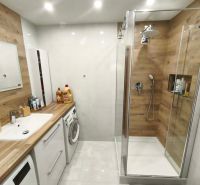 Badezimmer mit Holzboden in einer 3-Zimmer-Wohnung, moderne Ausstattung und Duschkabine.