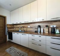 Küche in einer 3-Zimmer-Wohnung mit weißen Schränken und einem Boden in Holzoptik.