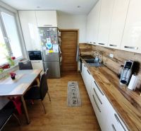 Küche in einer 3-Zimmer-Wohnung mit Holzboden, Tisch und moderner Ausstattung.