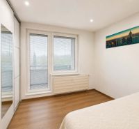 Schlafzimmer in einer 3-Zimmer-Wohnung mit Bett, Einbauschrank und Boden mit Holzdekor.