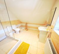 Helles Badezimmer in einer Hütte mit Badewanne und Waschbecken, ergänzt durch helle Fliesen.