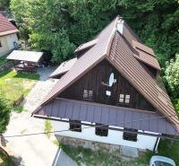 Ein Einfamilienhaus in Špania Dolina mit Holzverkleidung und einer Umgebung voller Grün.