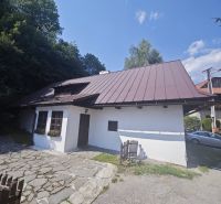Ein Familienhaus in Špania Dolina mit einem Steinweg und einem Holzzaun, umgeben von Natur.
