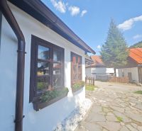Eine Hütte in Špania Dolina mit einem Blumenbeet am Fenster und einem gepflasterten Weg.