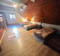 Ein Dachzimmer in einer Hütte mit einem Boden in Holzoptik und mehreren Betten.