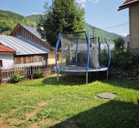Trampolin bei der Hütte in Špania Dolina, umgeben von Gras und Bäumen im Hintergrund.