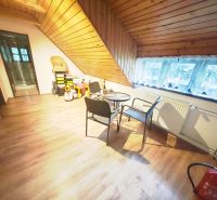 Boden mit Holzdekor, Sitzgelegenheiten, Kinderspielzeug und schräges Dach in der Hütte.