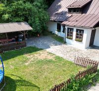 Ein Einfamilienhaus in Špania Dolina mit Garten, Rasen, Trampolin und einem hölzernen Pavillon in der Natur.