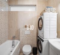 Badezimmer in einer 2-Zimmer-Wohnung mit Waschmaschine, Trockner, Badewanne und Toilette.