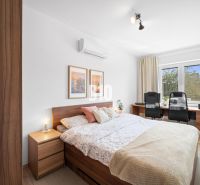 Schlafzimmer in einer 2-Zimmer-Wohnung mit Holzboden und Schreibtisch.