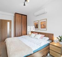 Schlafzimmer mit Bett, Kommode und Holzboden in einer 2-Zimmer-Wohnung.