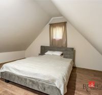 Dachbodenschlafzimmer in der Hütte mit einem Bett und einem Boden in Holzoptik.