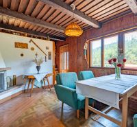 Das Innere der Hütte mit Holzelementen, Kamin und Blumen auf dem Tisch wirkt gemütlich.