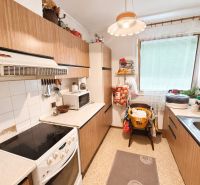 Die Küche im Einfamilienhaus hat einfache Möbel mit Holzdekor und weiße Elektrogeräte.