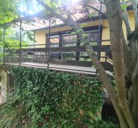 Ein Einfamilienhaus in Svodín, umgeben von dichtem Grün, mit einer Terrasse, die von Kletterpflanzen bewachsen ist.