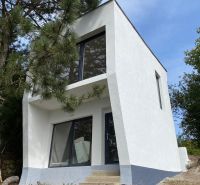 Eine moderne weiße Hütte in Šahy, umgeben von Natur und Kiefern.