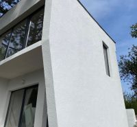 Ein Ferienhaus in Šahy mit markanten Verglasungen und weißer Fassade.