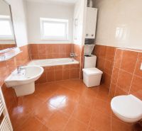 Badezimmer mit Badewanne, Waschbecken, Toilette und Waschmaschine in einer Einzimmerwohnung.