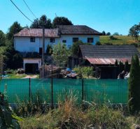 Ein Einfamilienhaus in Stará Turá mit Garten, Umzäunung und Anbauten, mit Blick auf die Landschaft.