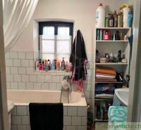 Badezimmer in einem Einfamilienhaus mit Badewanne, Regalen und verschiedenen Toilettenartikeln.