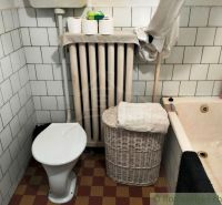 Ein Badezimmer in einem Einfamilienhaus mit Badewanne, Toilette, Heizkörper und Aufbewahrungskorb.