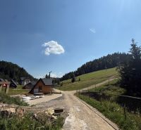 Freizeitgrundstücke in Litmanová mit Wald- und Hausszenerie, blauer Himmel.