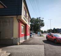 Geschäftsräume in der Straße SNP in Šaľa mit einem roten Auto auf der Straße.
