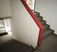 Eine Treppe mit einem roten Geländer in Geschäftsräumen, Boden mit Fliesen.