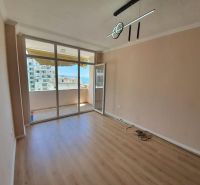 Ferienwohnung mit Glaswand und Boden in Holzoptik, Zugang zum Balkon.