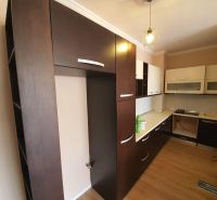 Küche in der Ferienwohnung, dominiert von dunklen Schränken und einem Boden mit Holzdekor.