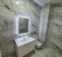 Badezimmer in der Ferienwohnung mit Marmordekor und Spiegel mit LED-Beleuchtung.