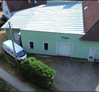 Produktionsräume in Budča mit grüner Fassade und Garagentor.