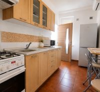 Küche in einer 2-Zimmer-Wohnung mit Holzschränken, Herd und Esstisch.
