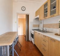 Küche in einer 2-Zimmer-Wohnung mit Holzschränken und Mikrowelle.