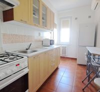 Küche in einer 2-Zimmer-Wohnung mit Gasherd, Spüle und Esstisch mit Stühlen.