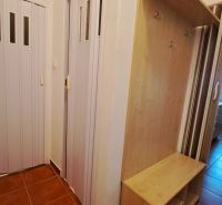 Eingang mit braunen Fliesen, Kleiderschrank und Schiebetüren in einer 2-Zimmer-Wohnung.