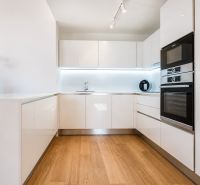 Küche in einer 3-Zimmer-Wohnung mit weißen Schränken und einem Boden in Holzoptik.
