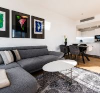 Wohnzimmer in einer 3-Zimmer-Wohnung mit einem bequemen Sofa, dekorativen Bildern und heller Einrichtung.