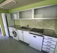 Küche in einer 3-Zimmer-Wohnung mit weißen Schränken und grünen Fliesen.