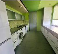 Küche in einer 3-Zimmer-Wohnung mit Waschmaschine, weißen Möbeln und grünen Wänden.