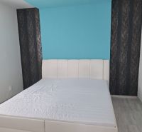 Helles Schlafzimmer mit weißem Bett und blauer Wand in einer 3-Zimmer-Wohnung.