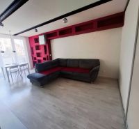 Wohnzimmer in einer 3-Zimmer-Wohnung mit Ecksofa, Esstisch und Boden in Holzoptik.