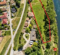 Freizeitgrundstücke in Hamuliakovo am Fluss, umgeben von Grün und Häusern.