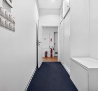 Ein Flur mit weißen Wänden und einem Boden in Holzoptik in Geschäftsräumen.