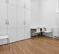 Weiße Schränke, Stühle und Tisch auf einem Boden mit Holzdekor in Geschäftsräumen.
