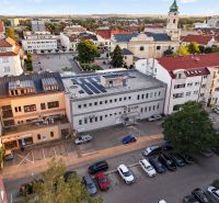 Blick auf M.R. Štefánik in Topoľčany mit Geschäftsräumen und einer Kirche im Hintergrund.