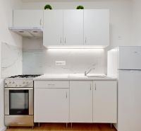 Kompakte Küche mit weißen Möbeln und Gasherd in einer 3-Zimmer-Wohnung.