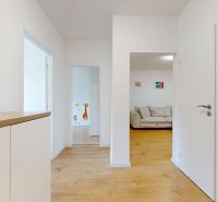 Der Flur in einer 3-Zimmer-Wohnung mit einem Holzboden und Wanddekorationen.
