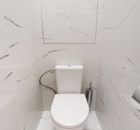 Badezimmer in einer 3-Zimmer-Wohnung mit Marmorfliesen und Toilette.
